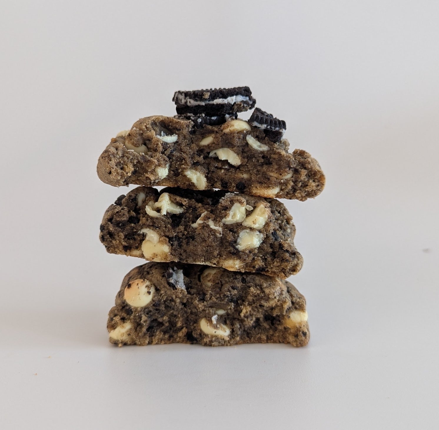 Stack of oreo cookies with visible white filling on a light gray background